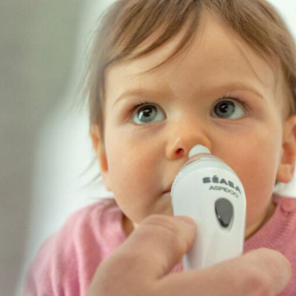 Child using a Beaba Aspidoo Nasal Aspirator with a blurred background