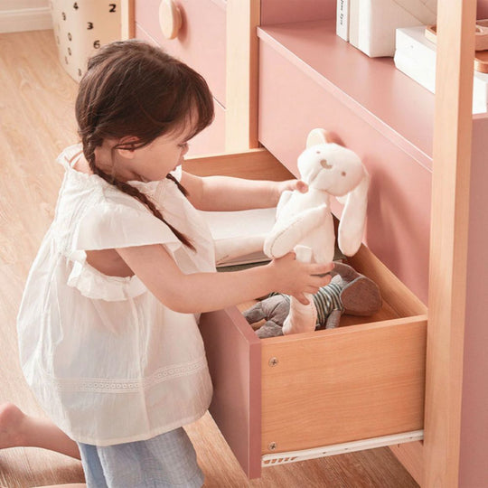 Child playing with toys in a pink and wooden toy storage unit
