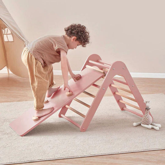 Child playing on a pink wooden climbing toy indoors