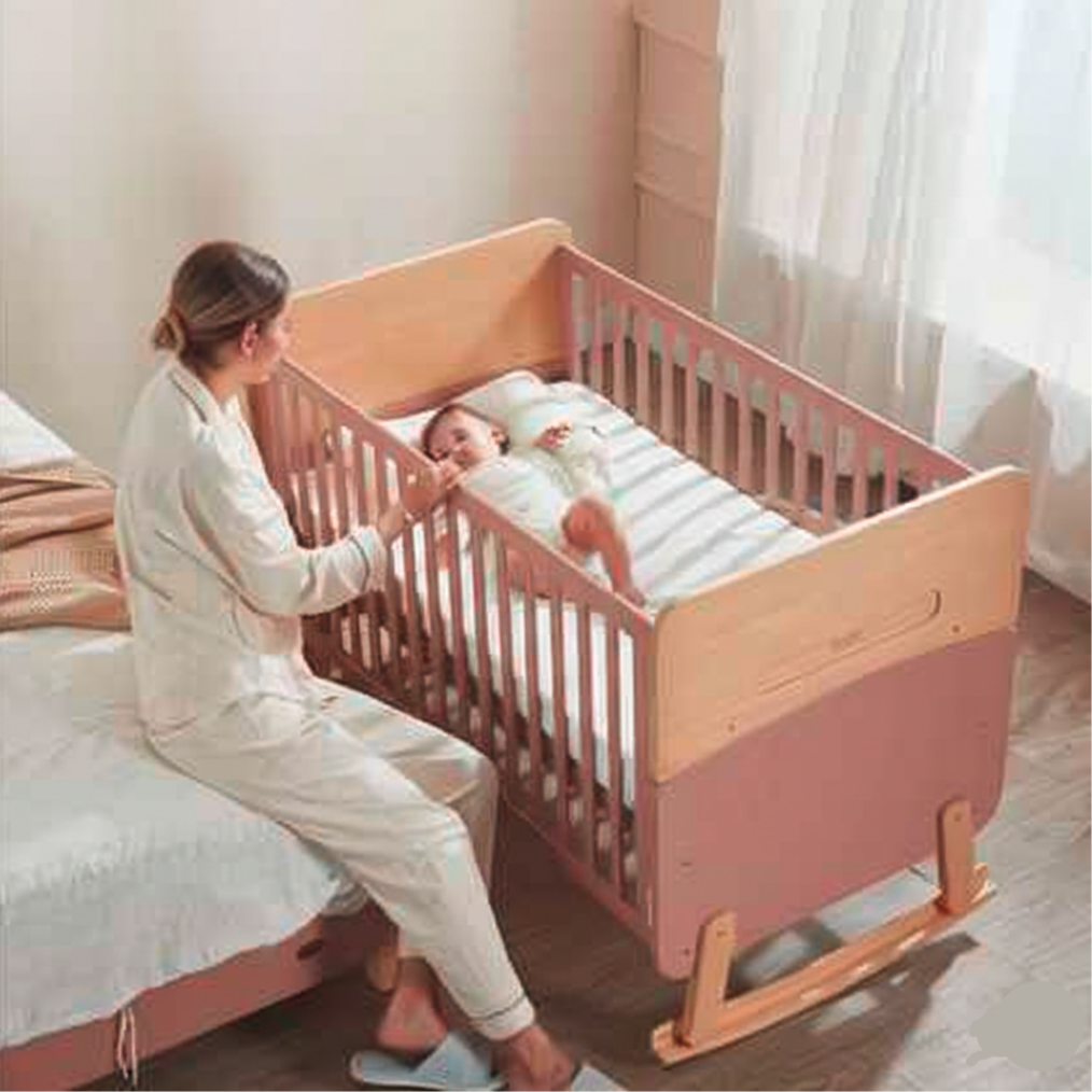 Woman sitting next to a baby in Boori Neat 5-in-1 Convertible Cot - Barley White & Almond in a bedroom setting.