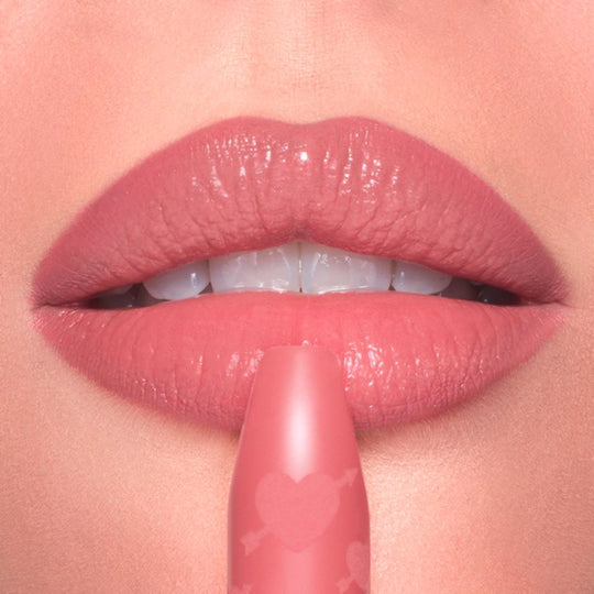 Close-up of lips being touched with a Charlotte Tilbury Pillow Talk Love Effect Lipstick Matte Revolution - Naughty Talk lipstick.