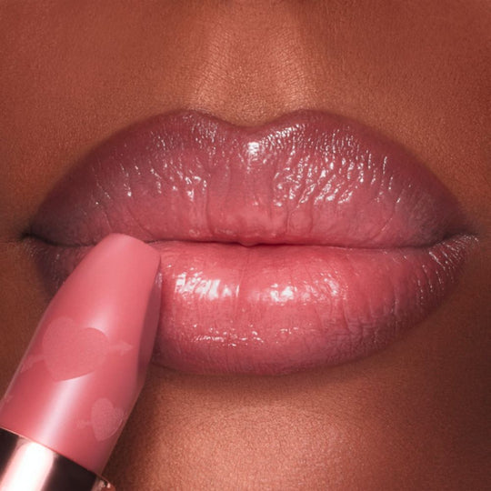 Close-up of lips being touched with a Charlotte Tilbury Pillow Talk Love Effect Lipstick Matte Revolution - Naughty Talk lipstick.