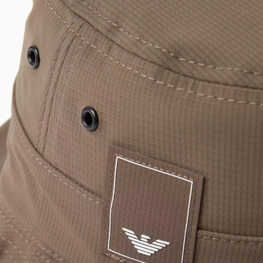 Close-up of a brown Emporio Armani bucket hat showing the logo patch and stitching detail