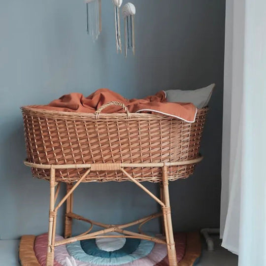 Wicker crib with a brown blanket against a gray wall
