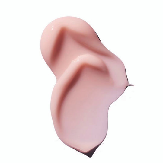 A high-angle, close-up shot of a thick, wavy swash of light pink cream against a plain white background. The cream has soft curves and a glossy finish, with some visible texture.