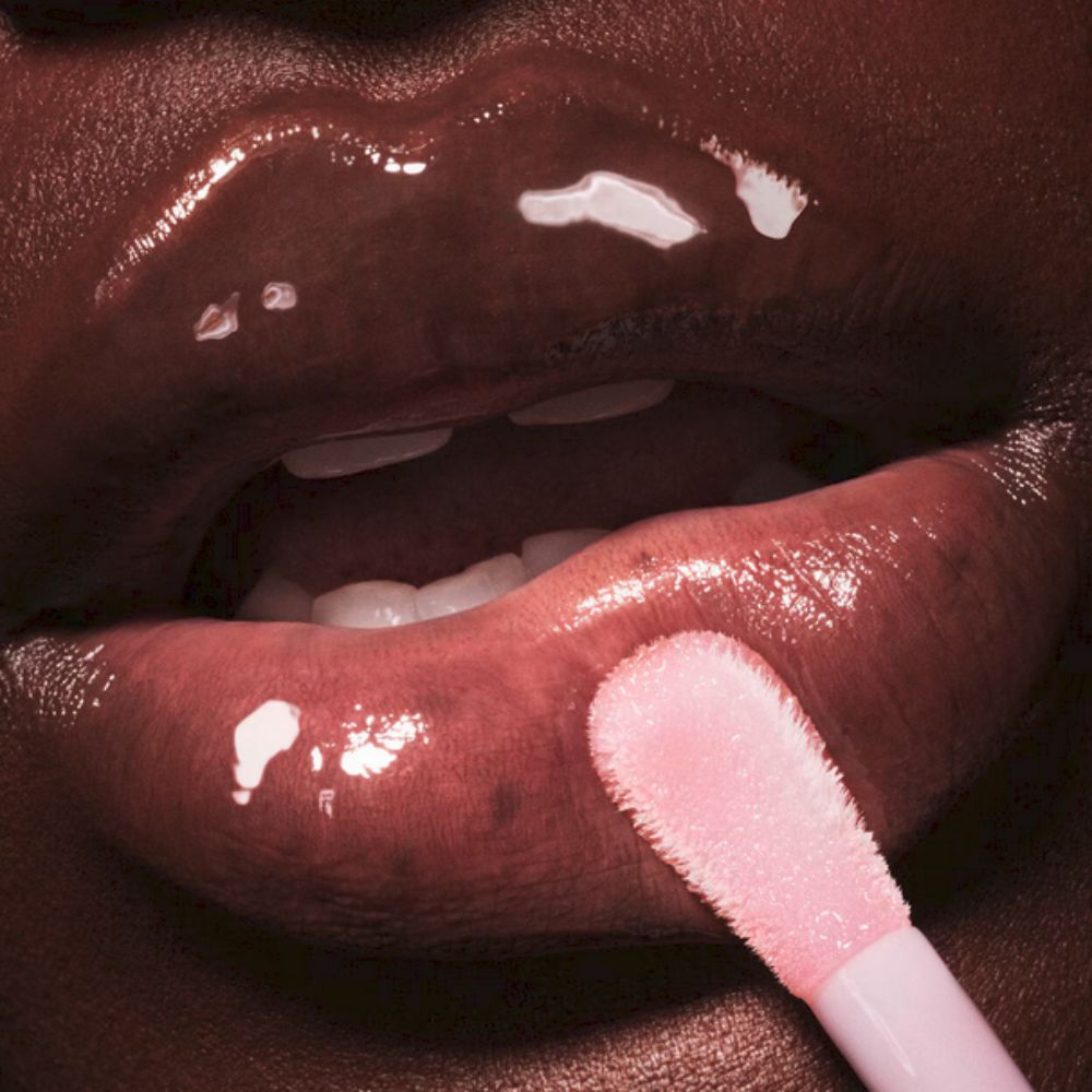 Close-up of a person's lips applying FENTY SKIN Fenty Treatz Hydrating + Strengthening Lip Oil, resulting in a wet, glossy finish