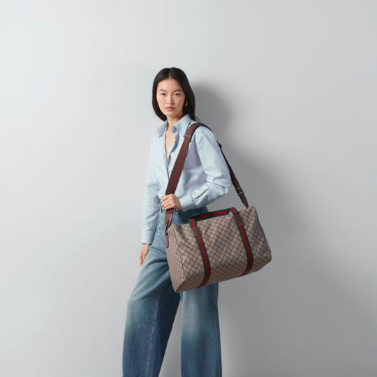 Beige Gucci duffle bag with GG Supreme pattern, brown leather trim, and green and red Web stripe.