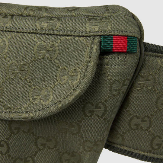 Close-up view of a forest green Gucci GG Canvas Large Belt Bag, showcasing the embossed GG monogram pattern on the canvas material. A small tag with the iconic green and red Web stripe detail is visible on the side. The stitching and texture of the canvas are clearly defined.