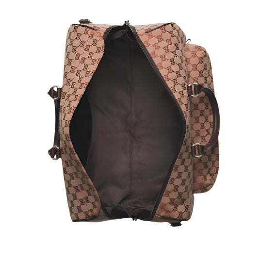 Overhead view of an open Gucci duffle bag, showing its GG canvas exterior, dark brown interior lining, brown leather handles, and a side pocket.