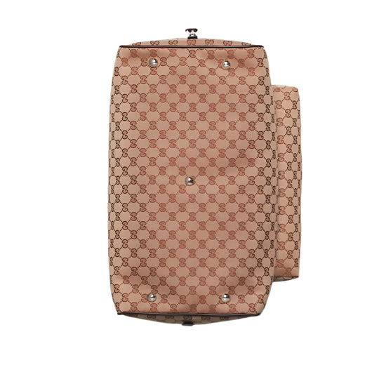 Overhead view of the bottom of a beige Gucci duffle bag, displaying its GG canvas pattern and five silver-toned protective feet. A side pocket is visible along the right edge.