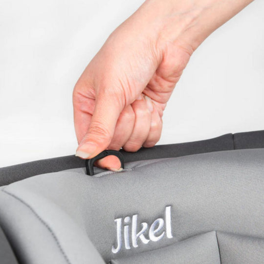 Hand adjusting a strap on a Jikel car seat with a plain background