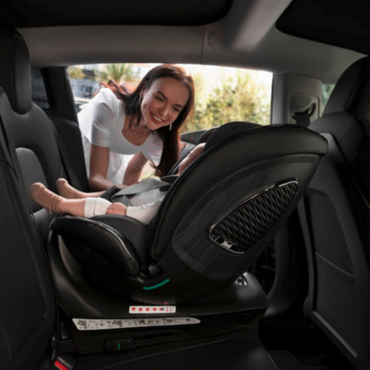 Woman adjusting a child's car seat in a car. This is a Jikel Neptune 360: Grey 360° i-Size Car Seat
