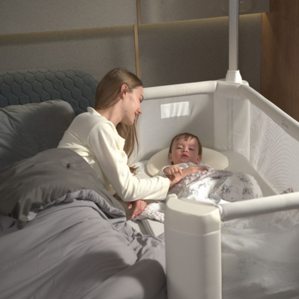 A mother consoles a baby who is sleeping in Jikel Braha Intelligent 7-in-1 Light Beige Baby Crib