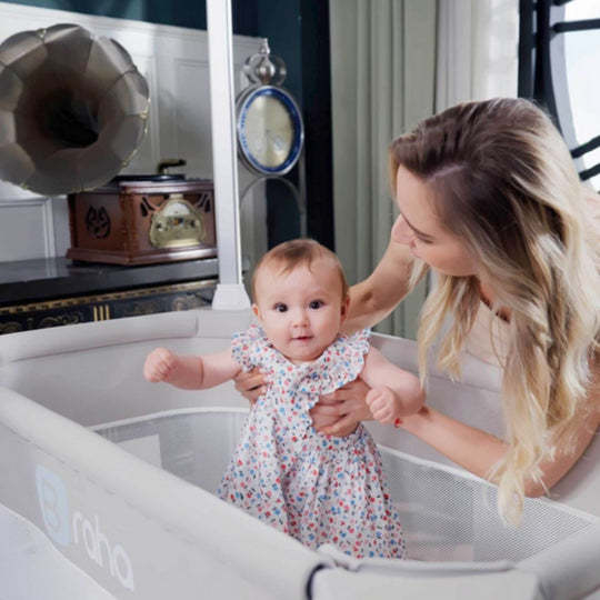 A mother playing with a baby girl standing in a Jikel Braha Intelligent 7-in-1 Light Beige Baby Crib