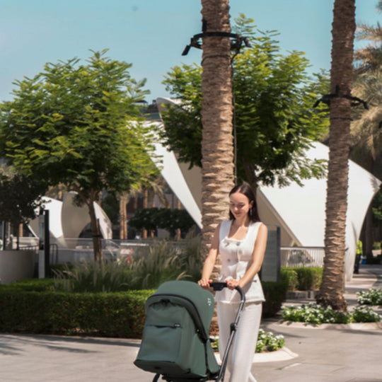 Woman pushing a Jikel Life 360 Reversible Stroller in a palm tree-lined area