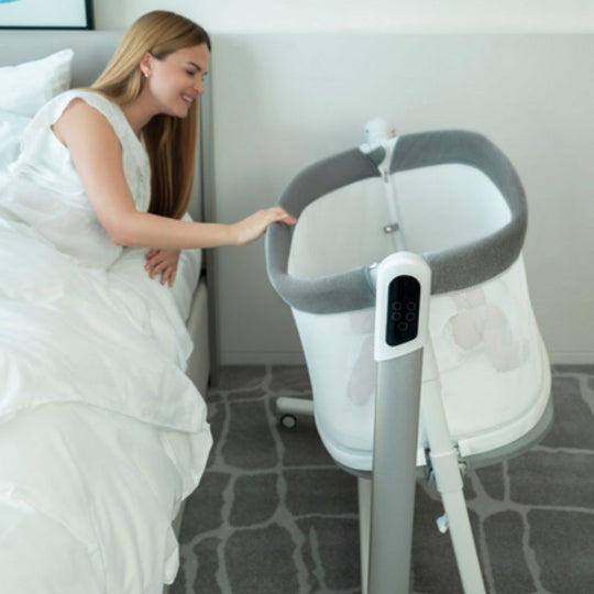 Woman interacting with a baby bassinet in a bedroom setting