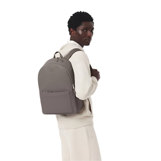 A black model standing with LACOSTE Chantaco Pique Leather Brown Backpack on his back