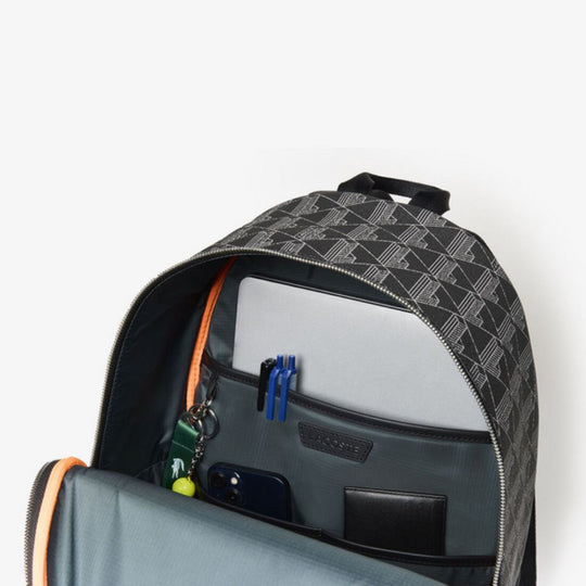 Opened Lacoste The Blend Backpack showing a laptop, smartphone, wallet, and pens in organized interior compartments.