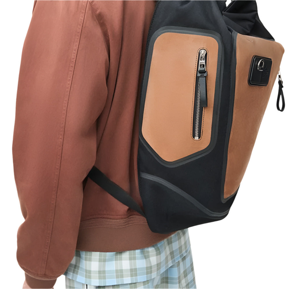 A person from behind wears a LOEWE Flex Roll-Top Backpack in black canvas and brown suede. He is wearing a brown jacket and light blue and white checkered Boxers.