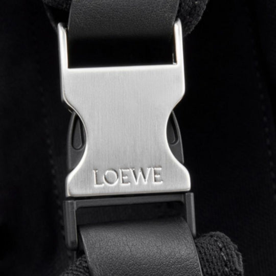A close-up shot of the metallic buckle on the LOEWE Flex Roll-Top Backpack.