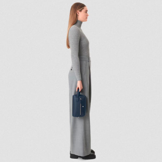 Woman in gray outfit holding Montblanc Sartorial Travel Wash Bag in Ink Blue Full-Grain Leather