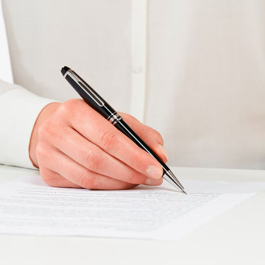 Close-up of a person's hand holding a black and silver Montblanc Meisterstück Classique Platinum-Coated Mechanical Pencil 0.5 mm, writing on a white document.