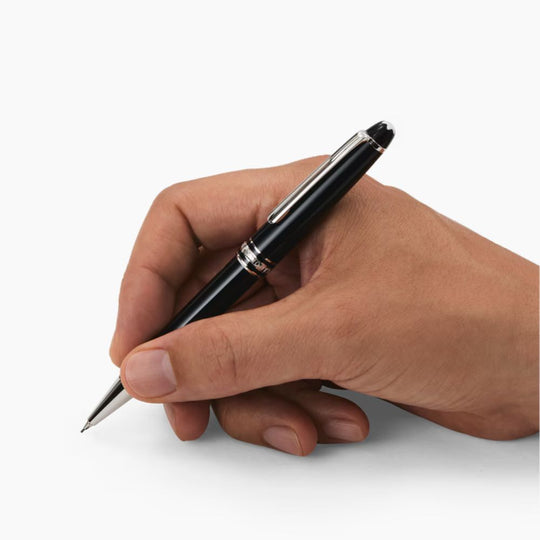 Hand holding and writing with a Montblanc Meisterstück Classique Platinum-Coated Mechanical Pencil 0.5 mm against a white background.