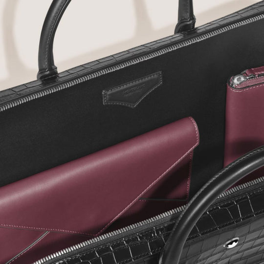 Close-up of a black handbag with a purple interior pocket.