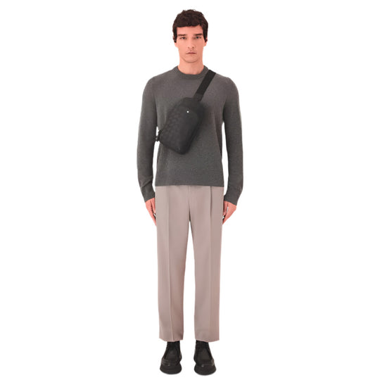 A man in a gray sweater and beige pants wears a black Montblanc Extreme 3.0 sling bag across his chest.