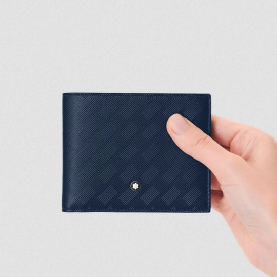 Hand holding a navy blue textured wallet against a light gray background