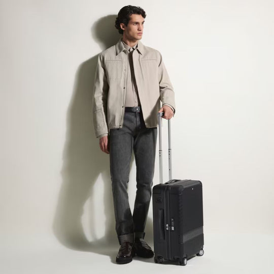 Man in beige jacket and gray pants standing next to Montblanc MY4810 Luxury Cabin Trolley Bag on a white background