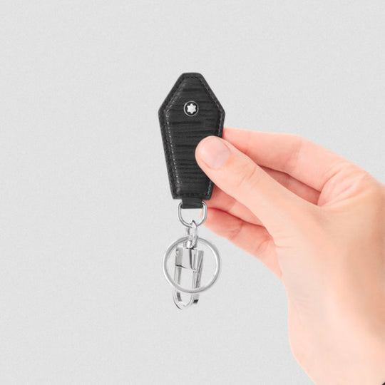 Hand holding a black keychain with a silver ring