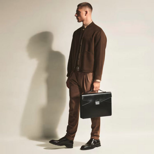 Man in a brown suit holding Montblanc Meisterstück Leather Flat Business Briefcase against a plain background