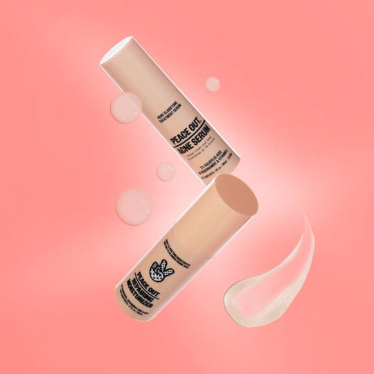 Two light peach-colored bottles, Peace Out Acne Serum and Peace Out Repairing Moisturizer, float diagonally on a pink background with floating bubbles and a smear of product.