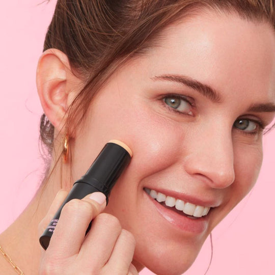 A model applying PEACE OUT SKINCARE Peace Out Retinol Face Stick on her cheek