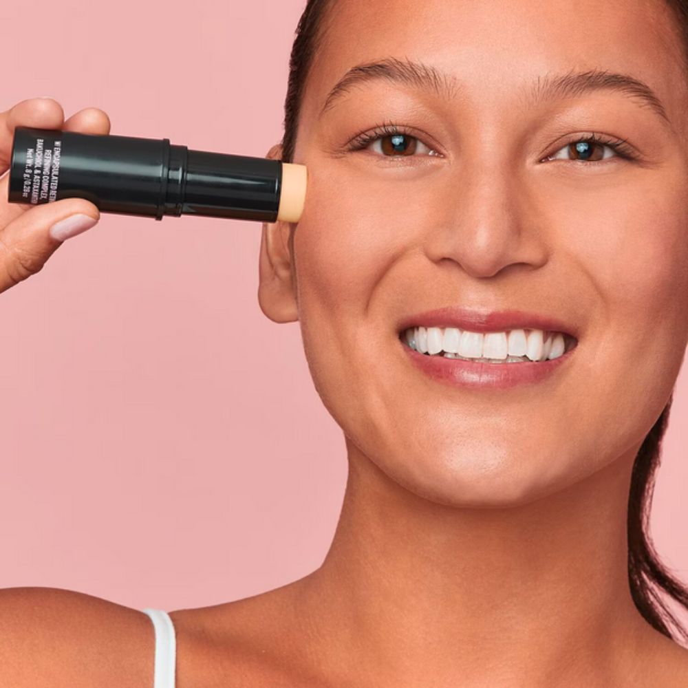 A model applying PEACE OUT SKINCARE Peace Out Retinol Face Stick on upper side of her right cheek