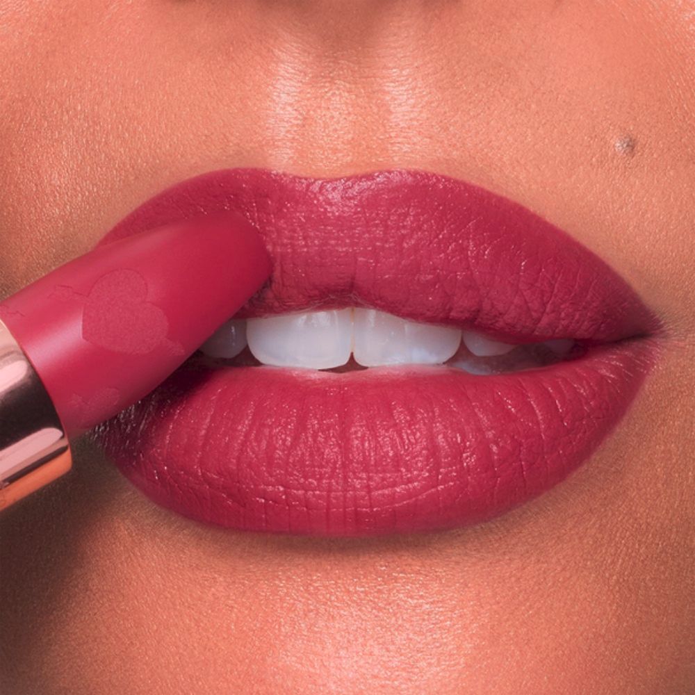 Close-up of lips being touched with a matte pink lipstick.