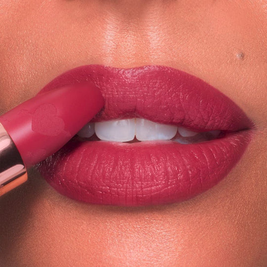 Close-up of lips being touched with a matte pink lipstick.