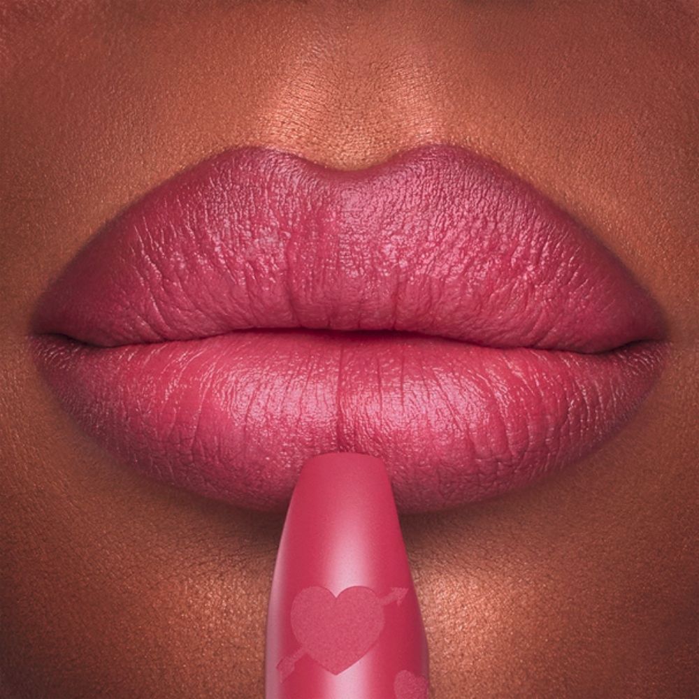 Close-up of lips being touched with a matte pink lipstick.