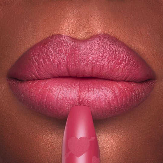 Close-up of lips being touched with a matte pink lipstick.
