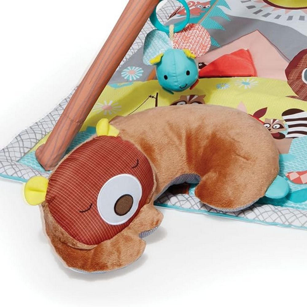 Plush toy caterpillar on a colorful play mat with toys in the background