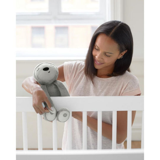 Woman holding a plush toy in front of a crib