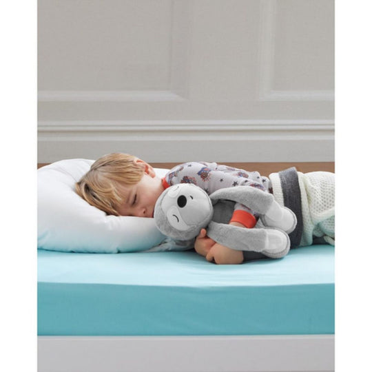 Child sleeping on a bed with a white pillow and blue mattress, holding a gray plush toy.