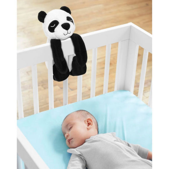 Baby sleeping in a crib with a panda plush toy hanging above