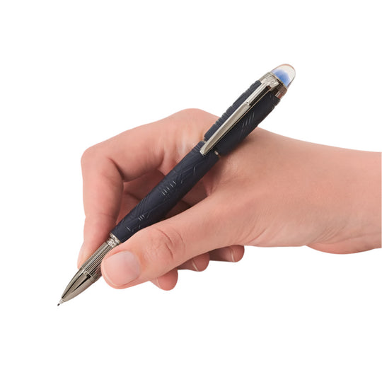 Close-up of a hand holding and writing with a Montblanc Starwalker SpaceBlue fineliner pen, showing the pen's textured blue barrel, ruthenium trim, and translucent cap top.