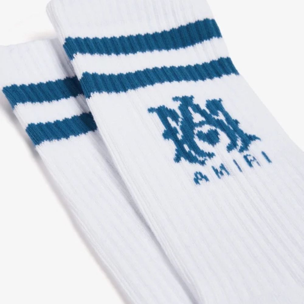 Close-up of white AMIRI socks with a black and white "MA" logo and blue stripes at the top