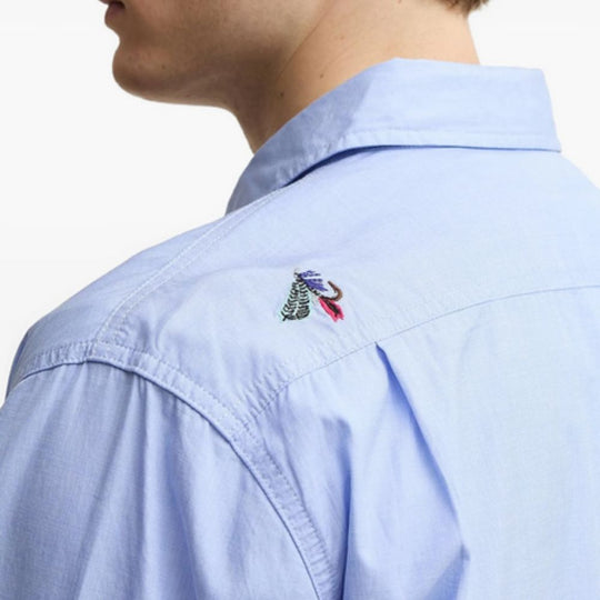Light blue shirt with a colorful embroidered logo on the chest.