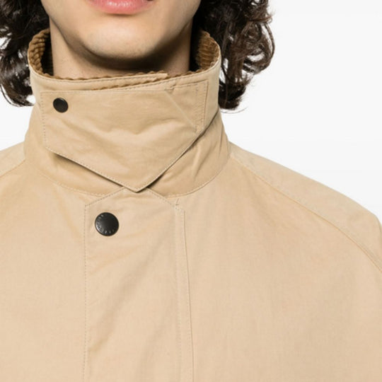 Close-up of a beige coat with a high collar and black buttons on a white background
