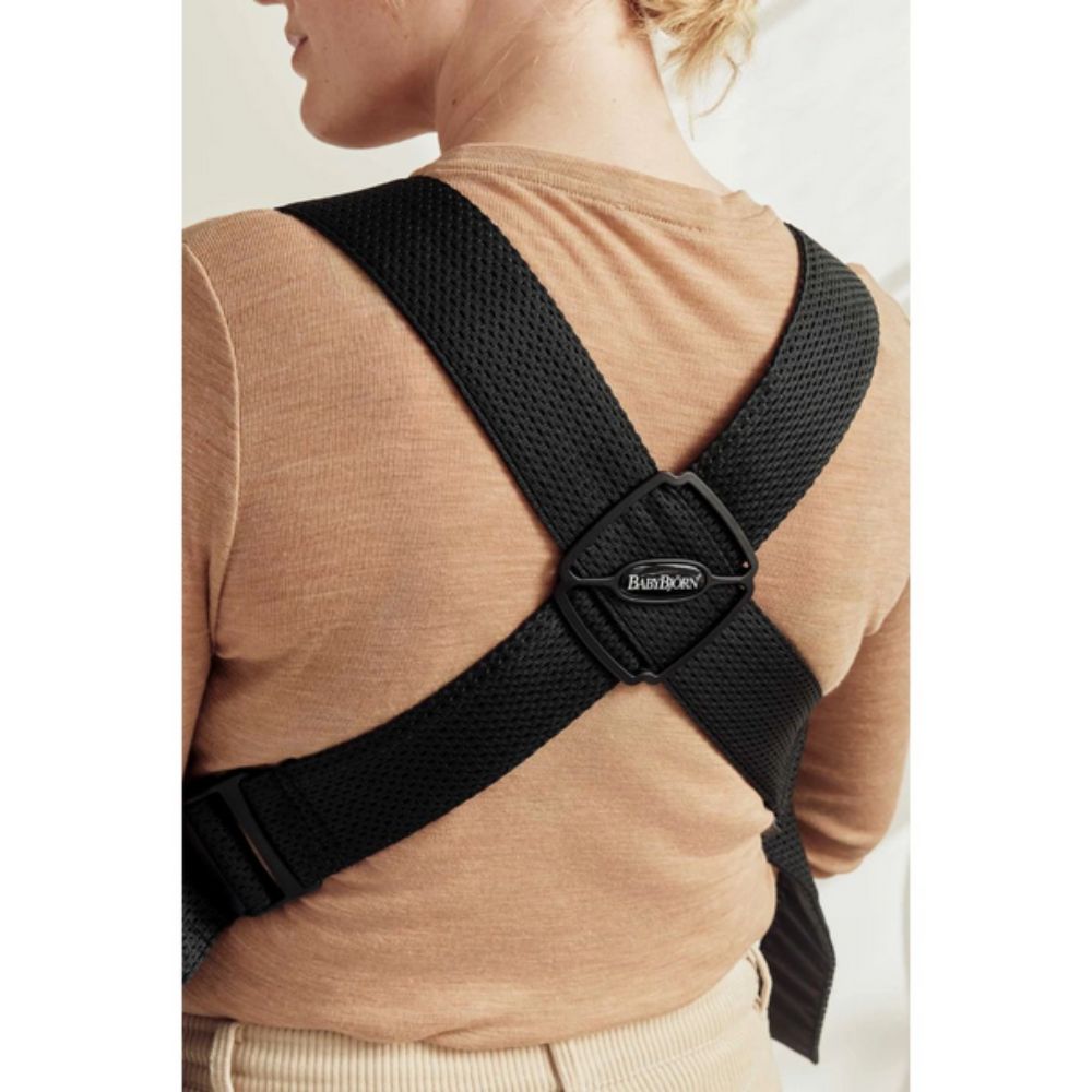 Person wearing a black posture corrector on a plain background