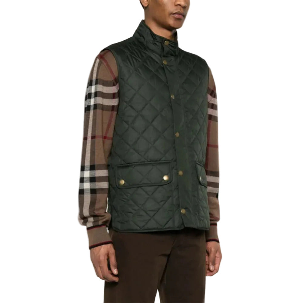 Man wearing a green quilted vest over a plaid shirt on a white background